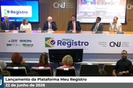 Uma imagem da transmissão ao vivo do evento "Lançamento da Plataforma Meu Registro", ocorrido em 22 de junho de 2026, promovido pelo Conselho Nacional de Justiça (CNJ). Ao fundo, seis autoridades estão sentadas em uma longa bancada branca que exibe o logotipo "meu Registro - Sistema Eletrônico dos Registros Públicos", acompanhado dos logos do CNJ e de outras entidades parceiras (ONR, ARCPN, IRTDPJ e SERP). À esquerda e à direita da bancada, telas exibem a marca do evento. Em primeiro plano, vê-se a parte de trás da cabeça de algumas pessoas na plateia e, no canto inferior direito, um intérprete de Libras. Uma barra informativa azul e cinza na parte inferior da tela exibe o logotipo do CNJ e o título do evento com a data.